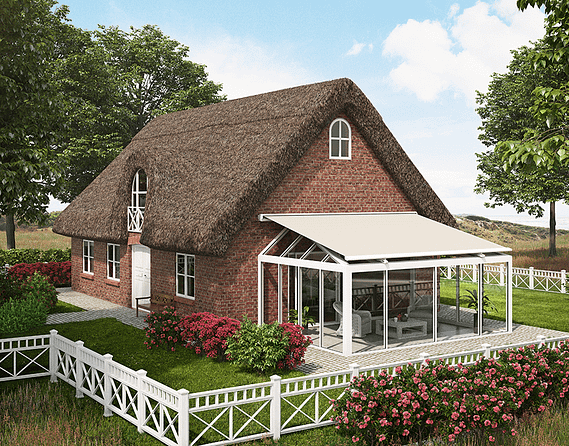 Ein Backsteinhaus mit Strohdach und einem weißen Zaun davor.