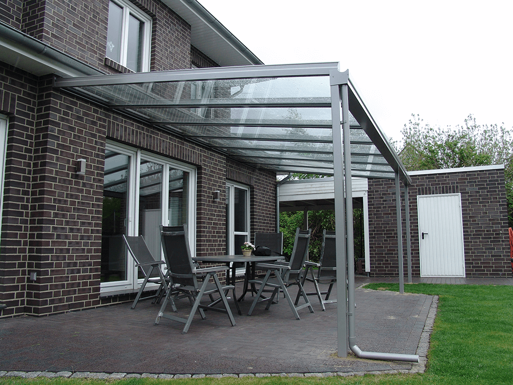 Eine Terrasse mit Tisch und Stühlen unter einem Glasdach