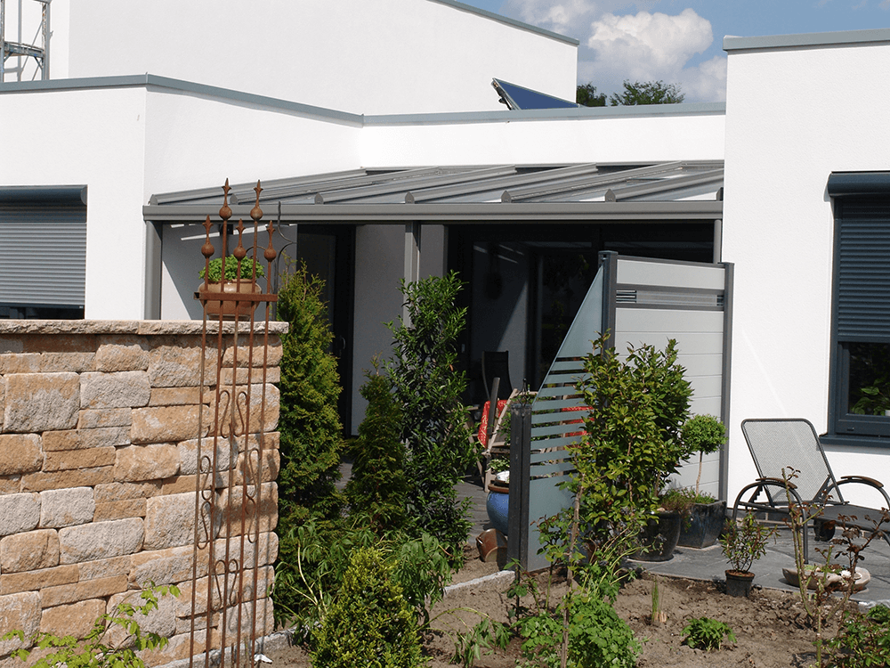 Ein weißes Haus mit einer Terrasse und einer Backsteinmauer