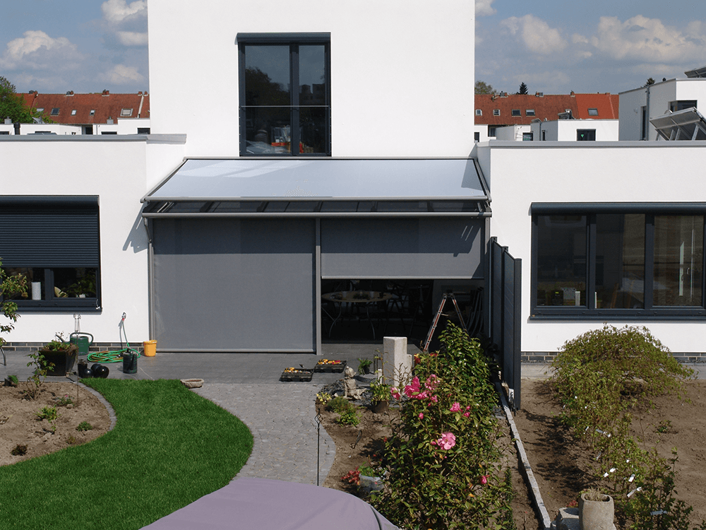 Ein weißes Haus mit einer grauen Markise an der Seite