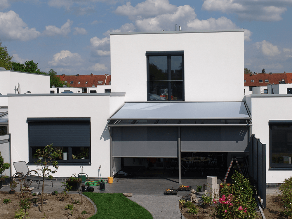 Ein weißes Haus mit einer grauen Markise auf dem Dach