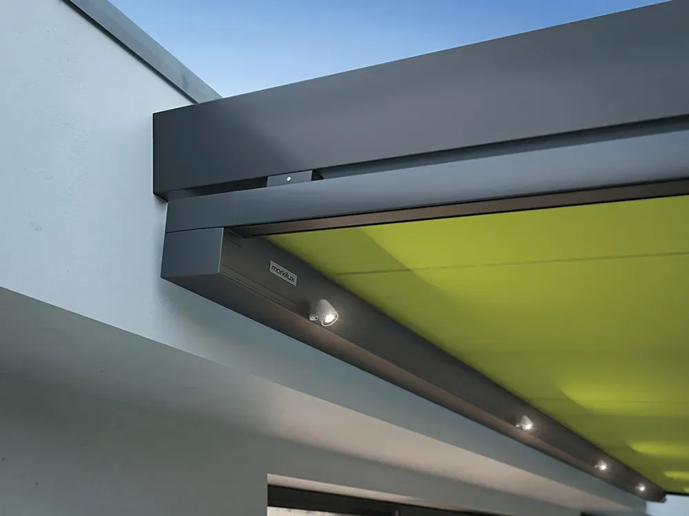 Eine grüne Markise hängt vom Dach eines Gebäudes.