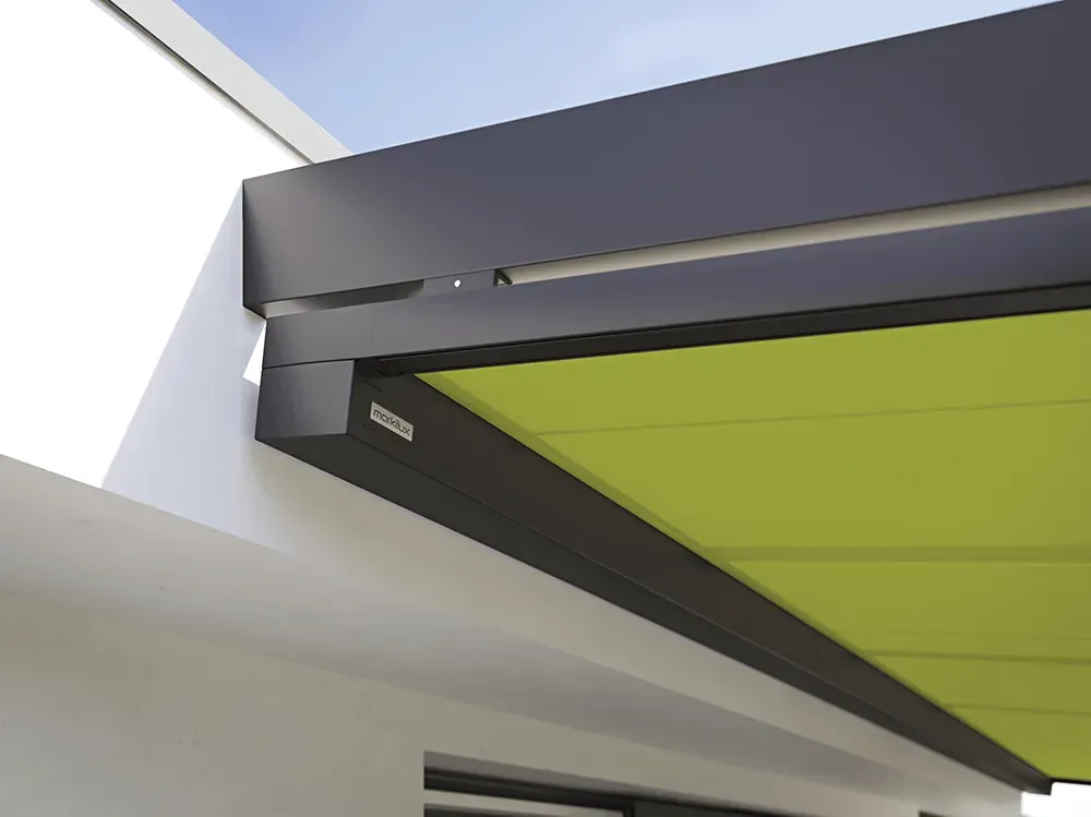 An der Seite eines Gebäudes befindet sich eine grüne Markise mit schwarzem Rahmen.