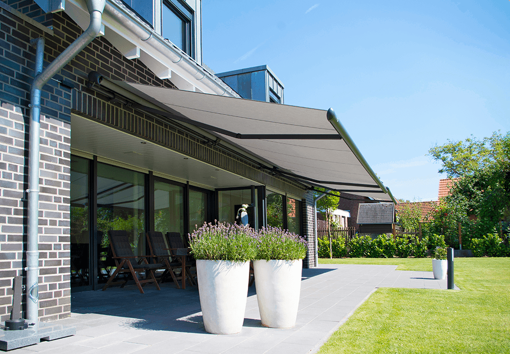 Eine Terrasse mit Überdachung und Topfpflanzen vor einem Backsteingebäude.