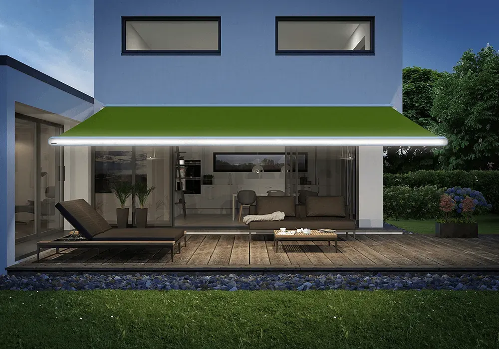 Ein Haus mit einer grünen Markise über der Terrasse bei Nacht.