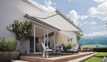 Eine Terrasse mit einer weißen Markise darüber und einem Haus im Hintergrund.