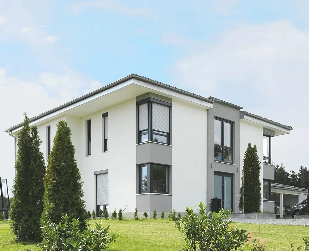 Ein weißes Haus mit vielen Fenstern und Bäumen davor