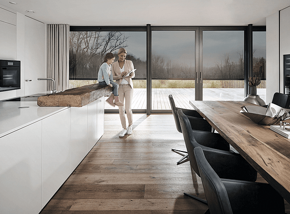 Eine Frau und ein Kind stehen in einer Küche und schauen auf ein Tablet.