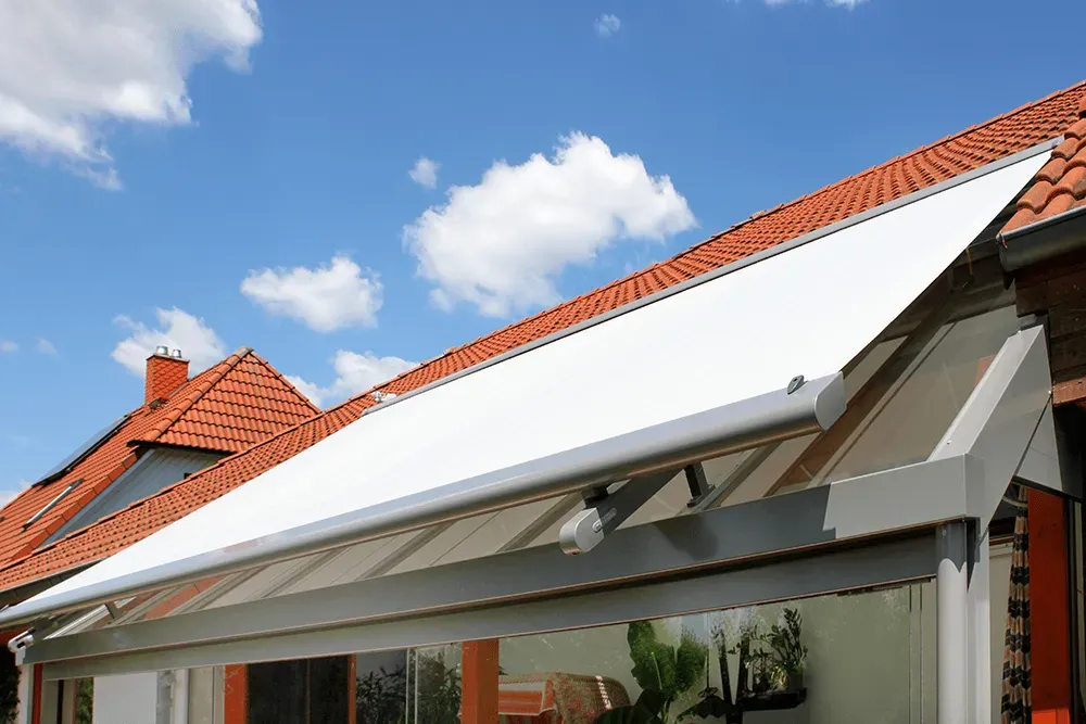 Eine weiße Markise hängt vom Dach eines Hauses