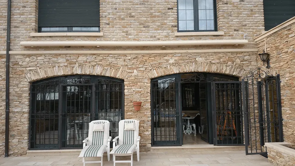 Zwei Liegestühle stehen auf einer Terrasse vor einem Backsteingebäude.