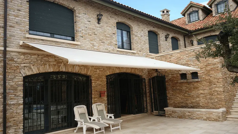 Ein großes Backsteingebäude mit einer weißen Markise über der Terrasse.