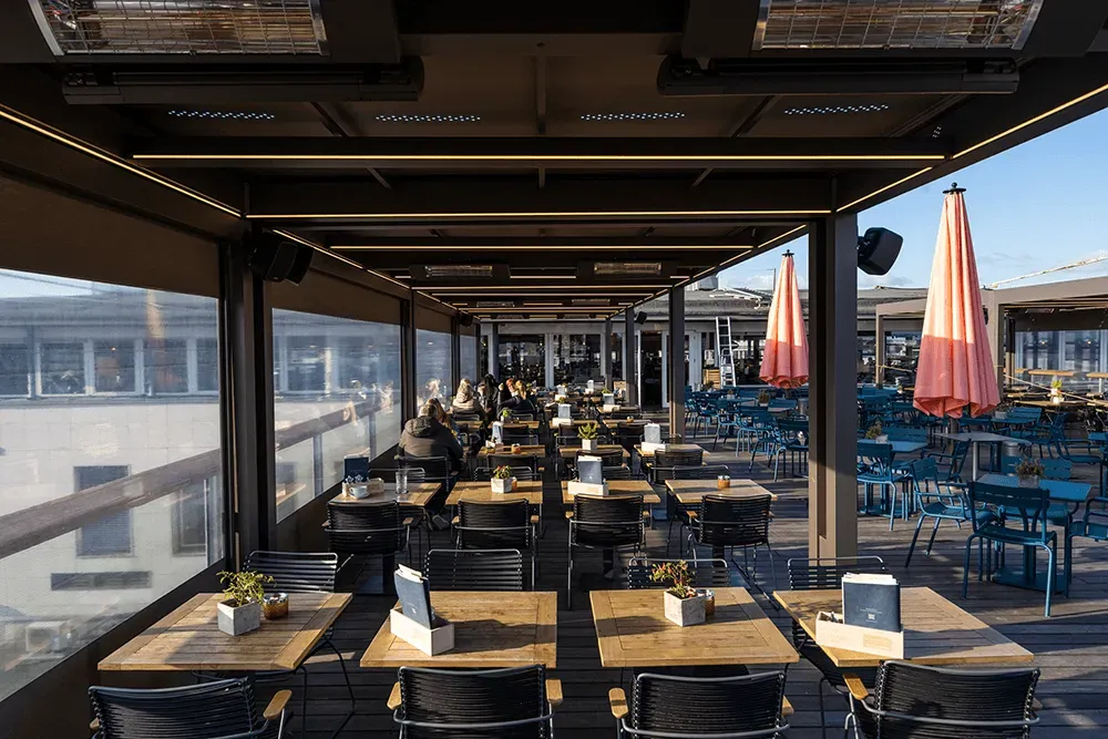 Ein Restaurant mit Tischen, Stühlen und Sonnenschirmen.