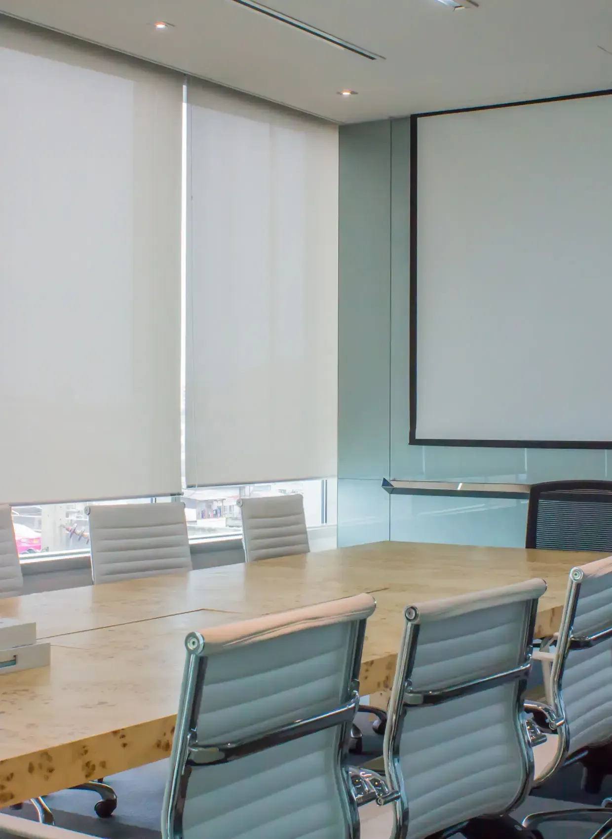 Ein Konferenzraum mit großem Tisch und Stühlen sowie einer Projektionsleinwand.