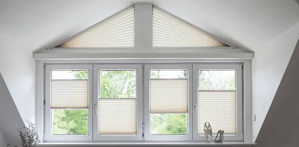 Ein Fenster mit dreieckigem Dach und Plissees.