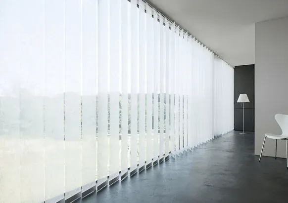 Ein langer Flur mit weißen Vertikaljalousien an den Fenstern.