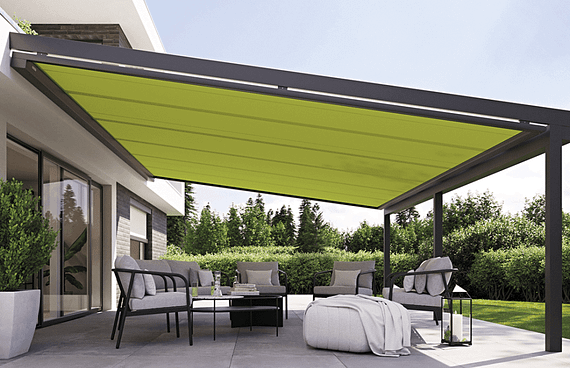 Eine Terrasse mit einer grünen Markise und einem Sofa und Stühlen darunter.