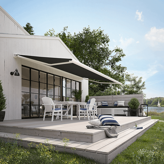 Ein weißes Haus mit einer schwarzen Markise über der Terrasse