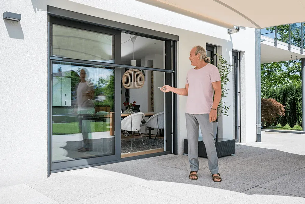 Ein Mann steht auf einer Terrasse vor einem Haus.