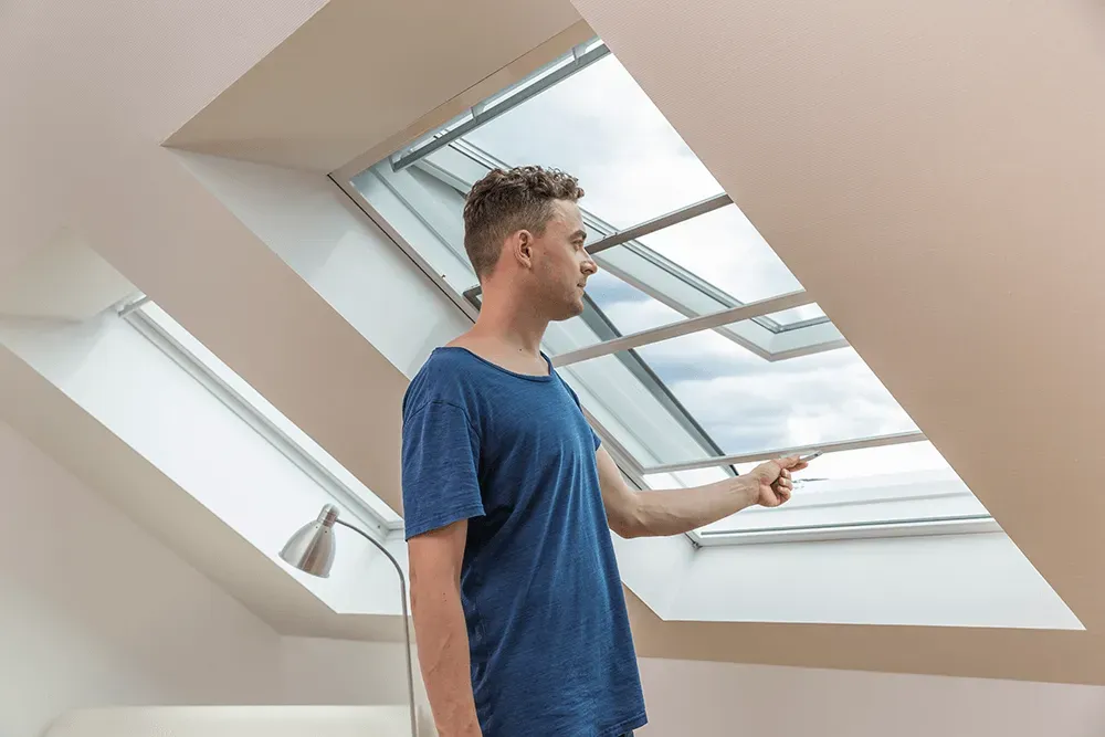 Ein Mann steht in einem Raum und schaut aus einem Oberlicht.