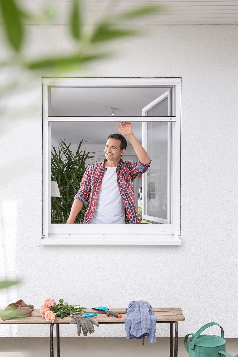 Ein Mann steht vor einem Fenster mit Fliegengitter.