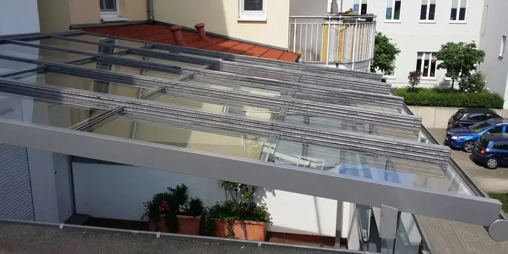 Eine Luftaufnahme eines Gebäudes mit Glasdach und davor geparkten Autos.