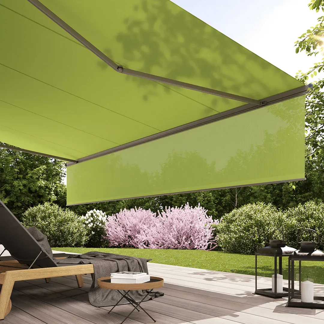 Eine grüne Markise überdacht eine Terrasse mit Stühlen und einem Tisch.