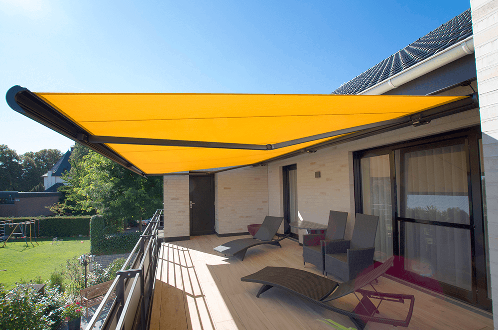 Ein Balkon mit gelber Markise und Liegestühlen