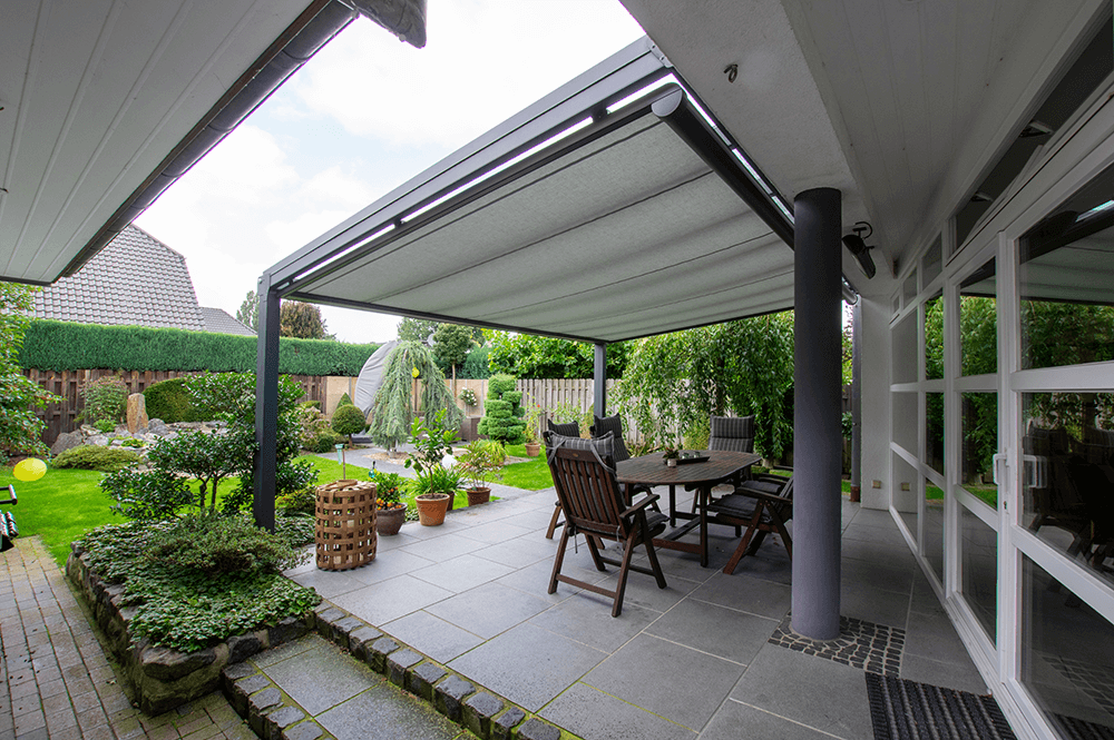 Eine Terrasse mit Tisch und Stühlen unter einem Baldachin.