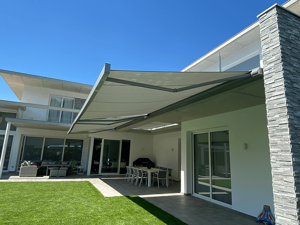 Ein großes weißes Haus mit einer großen Markise über der Terrasse.