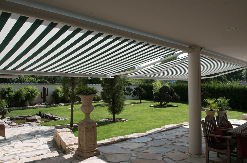Eine Terrasse mit einer grün-weiß gestreiften Markise darüber