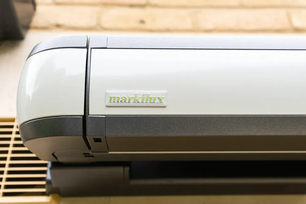 Auf einer Backsteinmauer steht eine weiß-graue Maschine.