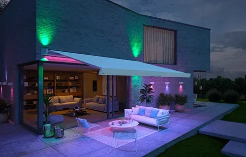 Ein Haus mit einer Terrasse und einem Vordach bei Nacht.