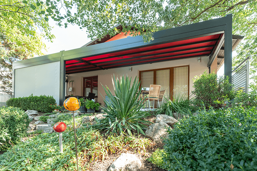 Ein Haus mit rotem Dach und einer Pergola im Hinterhof.