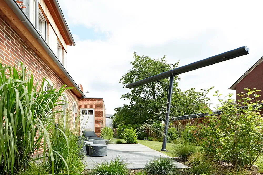 Ein Backsteinhaus mit Terrasse und Sonnenschirm davor.
