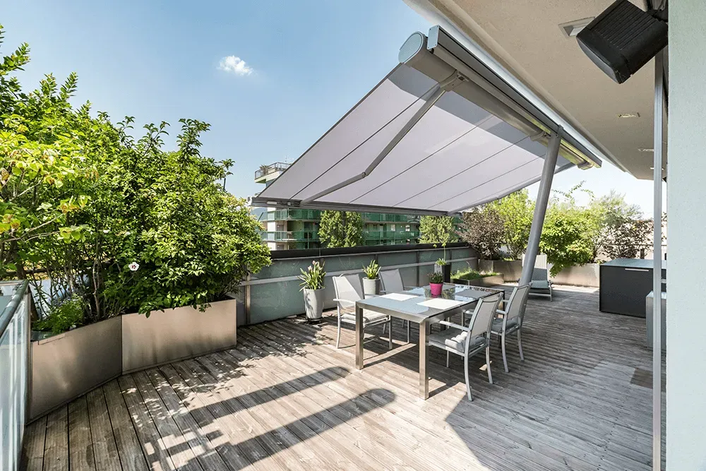 Eine Holzterrasse mit Tisch und Stühlen unter einem Sonnendach.