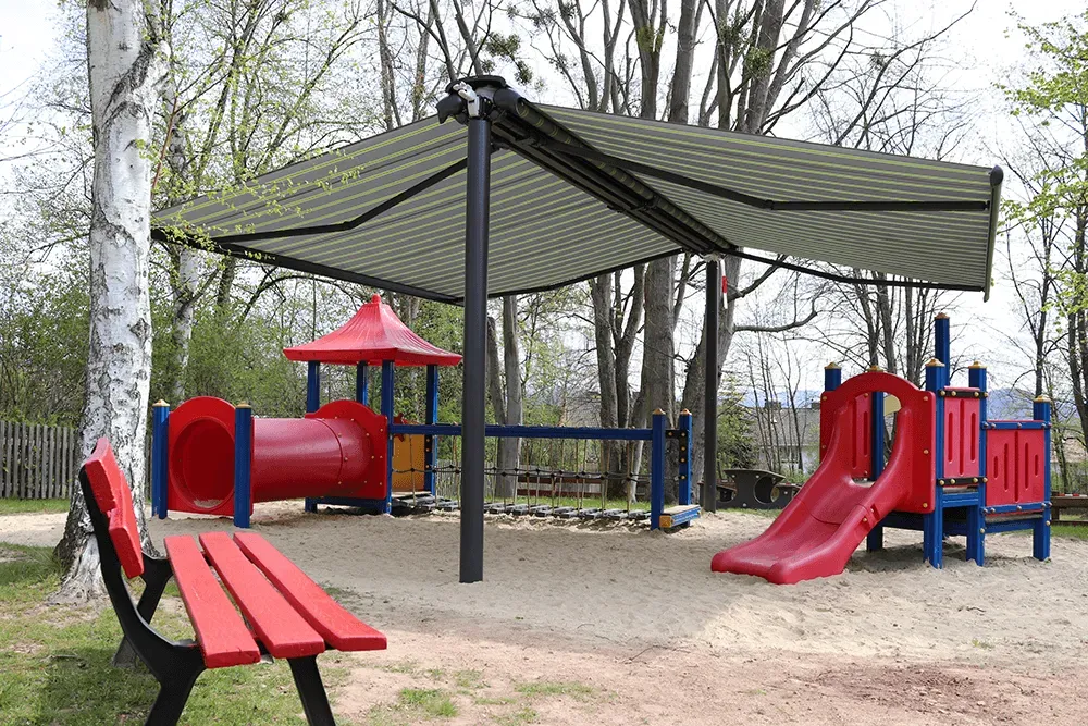 Ein Spielplatz mit Bank und Rutsche unter einem Vordach