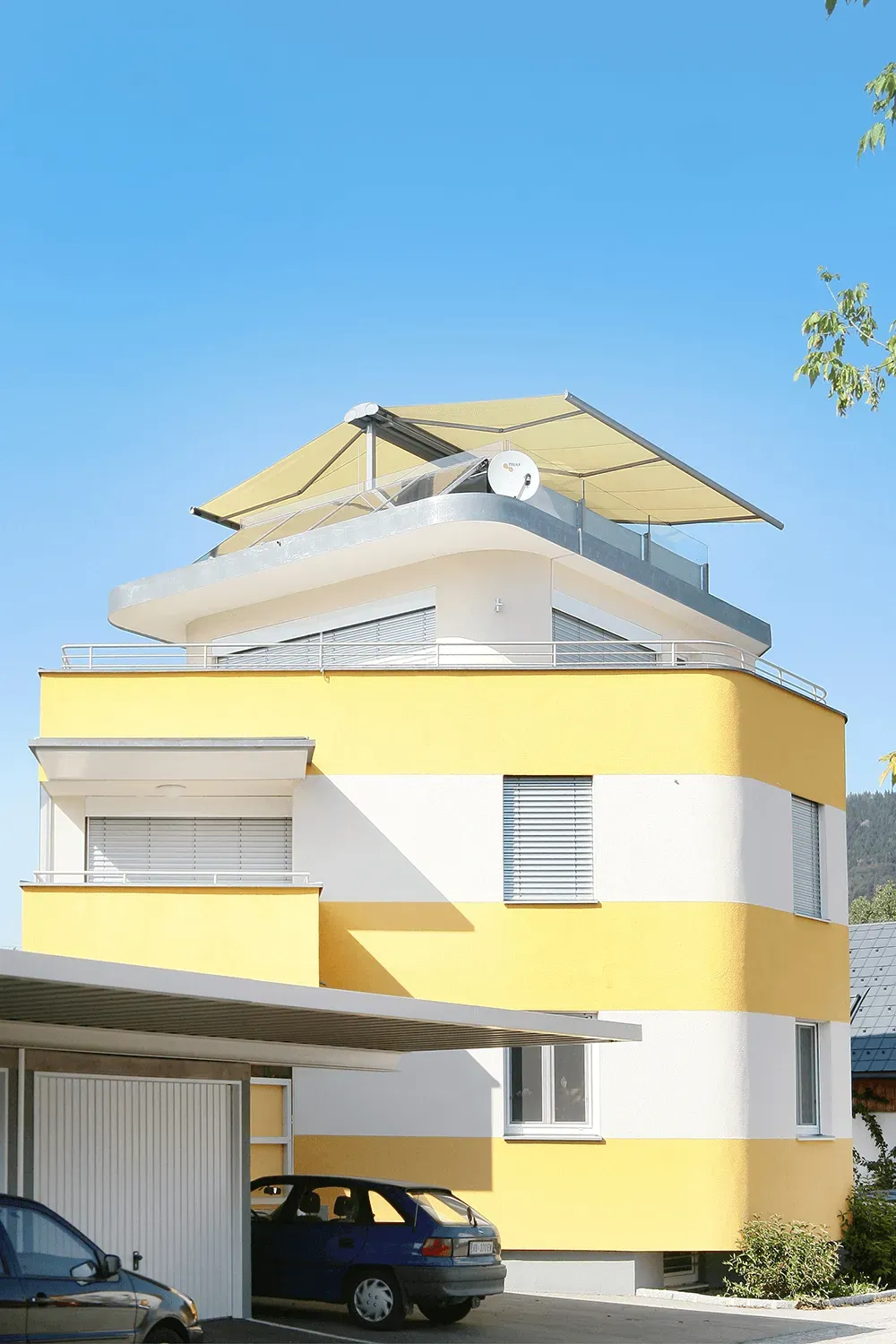Ein gelb-weißes Haus mit einem davor geparkten Auto