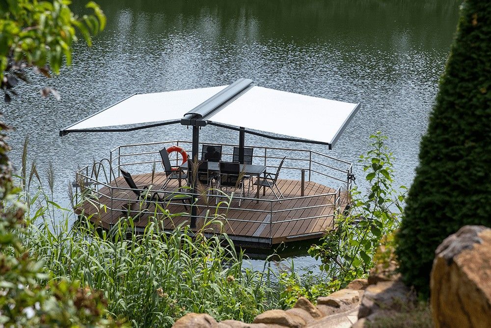 In der Mitte eines Sees befindet sich ein Steg mit einem Tisch und Stühlen.