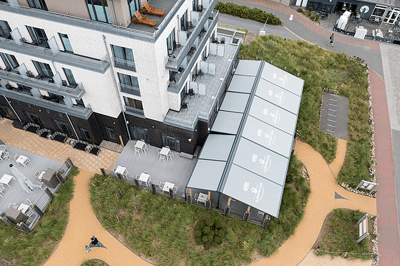 Eine Luftaufnahme eines Gebäudes mit Tischen und Stühlen davor.