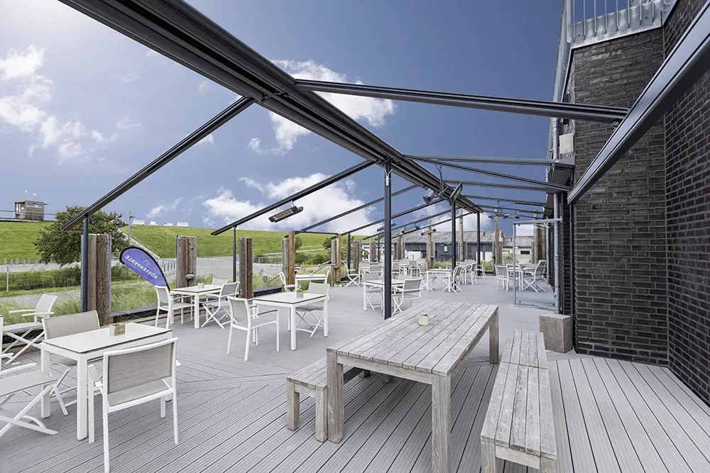 Eine große Terrasse mit Tischen und Stühlen unter einem Baldachin.