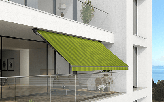 Ein Balkon mit grüner Markise und Blick aufs Meer.