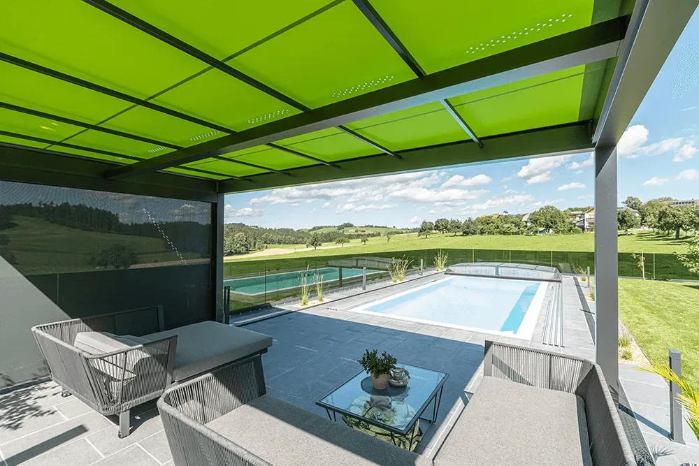 Eine Terrasse mit Gründach und einem Swimmingpool im Hintergrund.