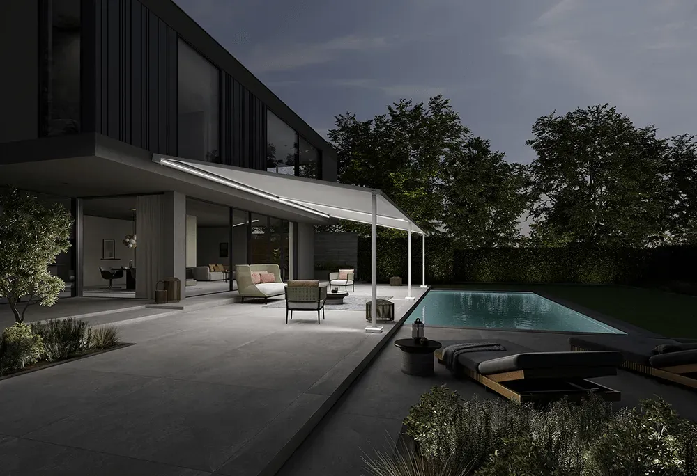 Ein großes Haus mit einem Swimmingpool im Hinterhof bei Nacht.