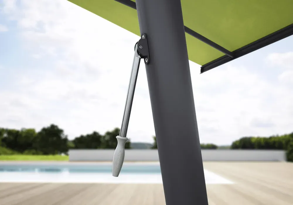 Ein grüner Sonnenschirm steht auf einem Holzdeck neben einem Pool.