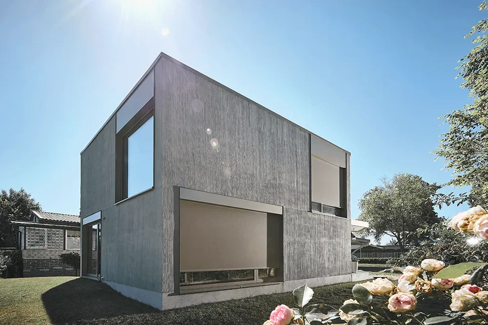 Ein modernes Haus mit vielen Fenstern steht inmitten eines üppig grünen Gartens.