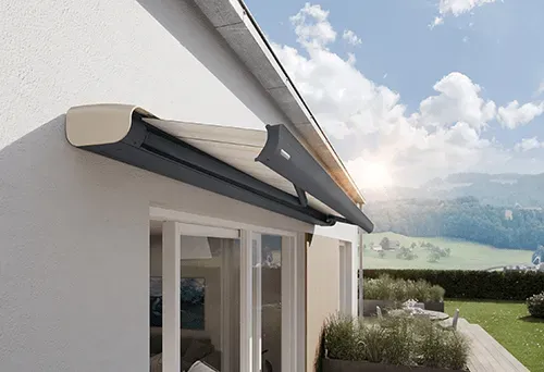 Ein weißes Haus mit einer schwarzen Markise an der Seite.