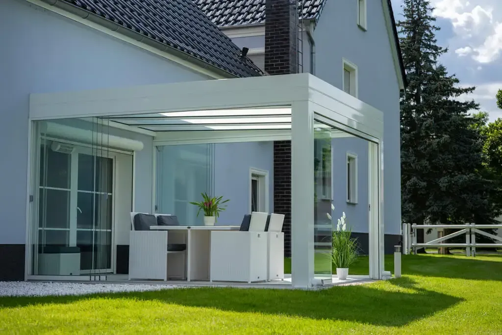 Ein blaues Haus mit einer weißen Pergola davor.