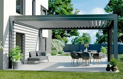 Eine Terrasse mit Tisch und Stühlen unter einer Pergola vor einem Haus.