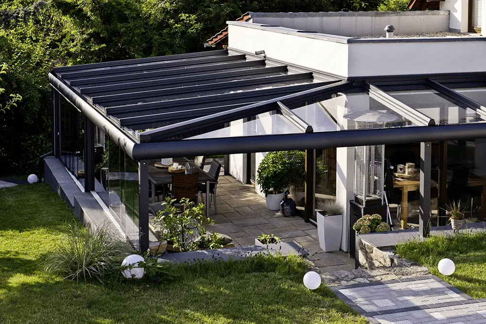 Ein Haus mit Pergola und Terrasse im Hinterhof.
