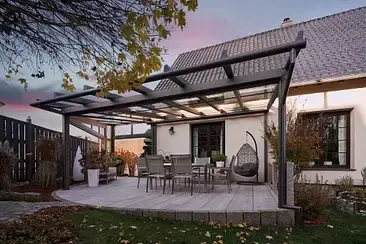 Es gibt eine Terrasse mit Tisch und Stühlen unter einer Pergola.
